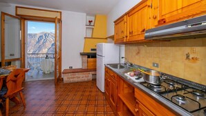 A kitchen with wooden cabinets, a stove, and a refrigerator. - Appartamento Secrel 9, Tremosine, Italy (Tremosine)
