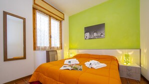 A hotel room with a large bed, a bedside table with a lamp, a window with curtains, and a framed picture on the wall. - Appartamento Secrel 9, Tremosine, Italy (Tremosine)