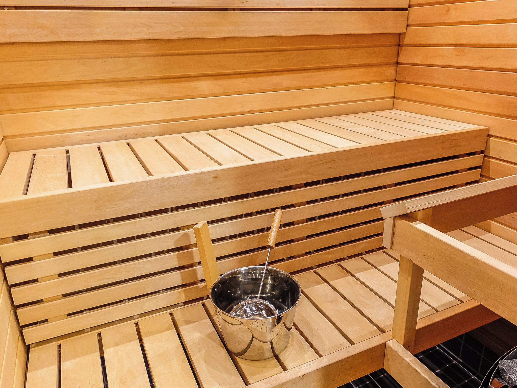 En sauna med træbænke og en metalspand.