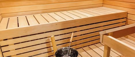 En sauna med træbænke og en metalspand.