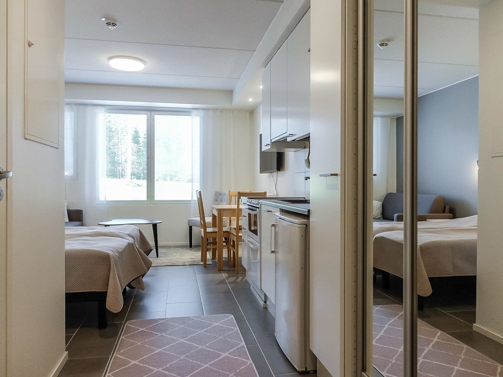 Et lille hotelværelse med tekøkken, spiseplads og seng.