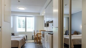 A compact hotel room with a kitchenette, a small dining area, and a bed. - Skistar 105 by Interhome (Kittilä)