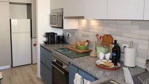 Uma cozinha moderna com uma pia de aço inoxidável, micro-ondas, torradeira e cafeteira.