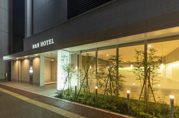 L'extérieur de l'hôtel R&B présente une façade moderne, de grandes fenêtres en verre et une entrée bien éclairée.