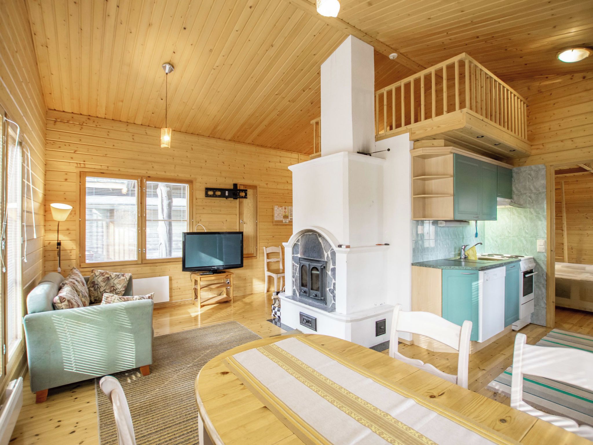 Ein gemütliches Blockhaus-Interieur mit Kamin aus Stein, Holzmöbeln und einer Küchenzeile.