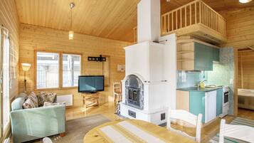Ein gemütliches Blockhaus-Interieur mit Kamin aus Stein, Holzmöbeln und einer Küchenzeile.