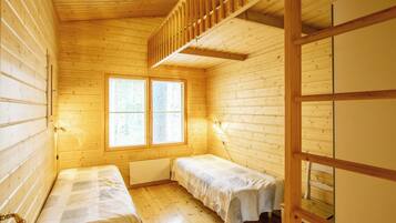 A cabin with two single beds, a window with blinds, wooden walls, and a wooden staircase.