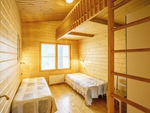 A cabin with two single beds, a window with blinds, wooden walls, and a wooden staircase.