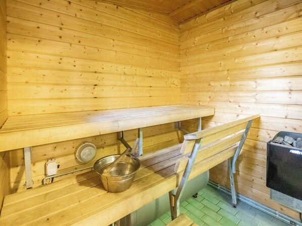 A wooden interior with a bench, a metal pot, and a grill.