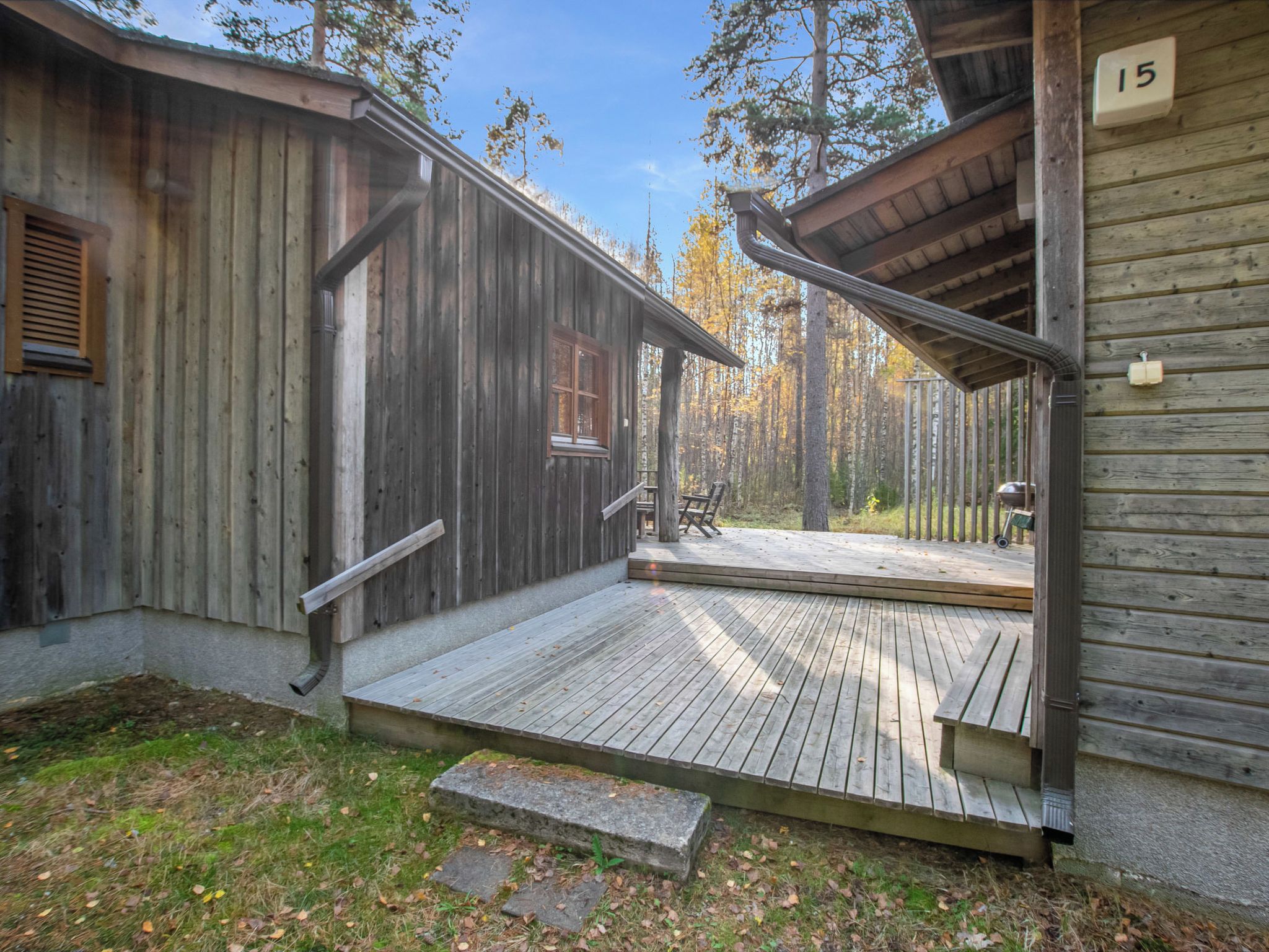 A wooden cabin with a porch, a number '15' sign, and a view of a forest.