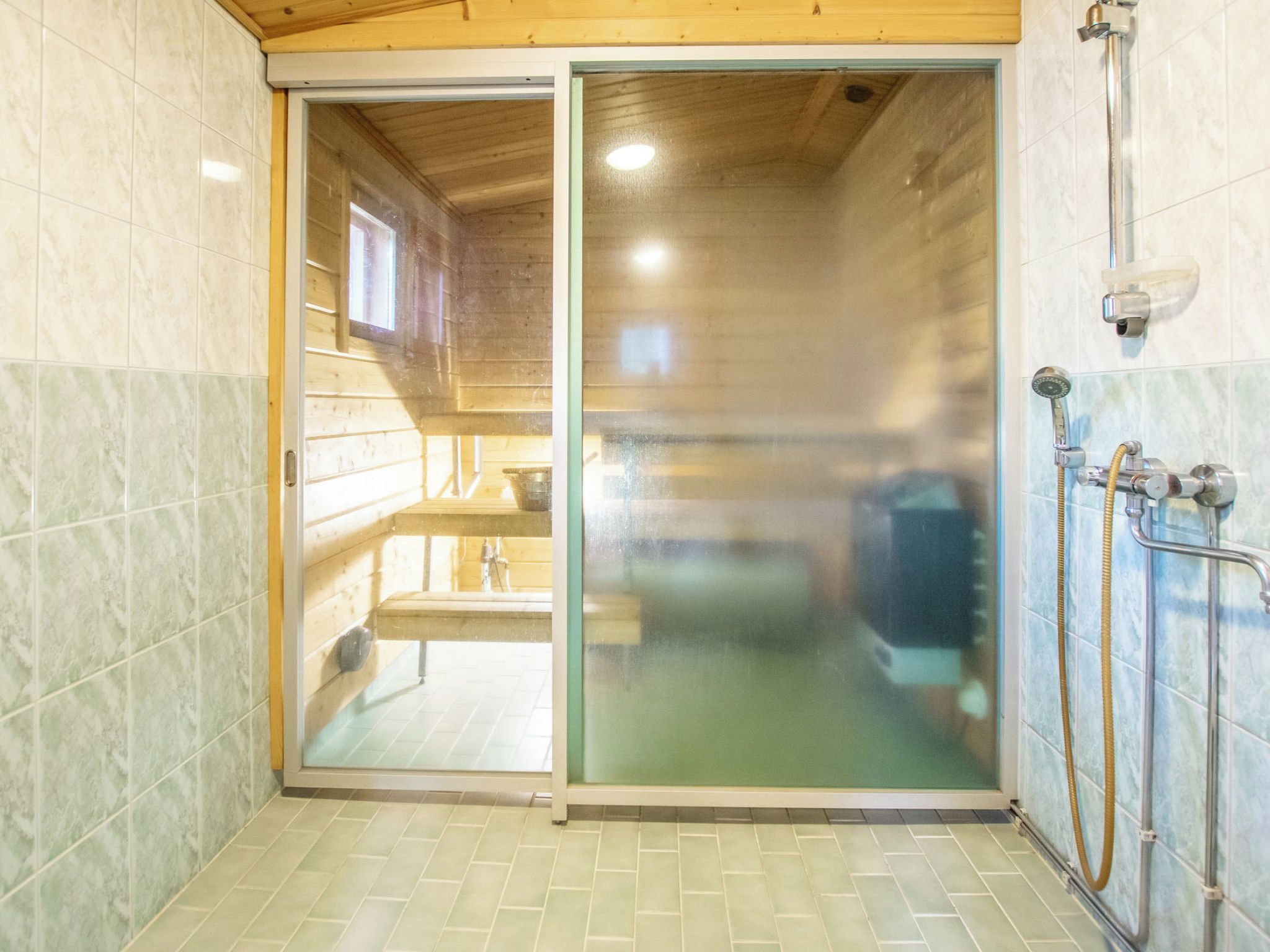 Une salle de bain avec une porte en verre, une douche et des toilettes.
