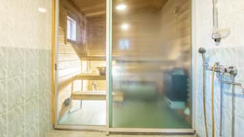 Une salle de bain avec une porte en verre, une douche et des toilettes.