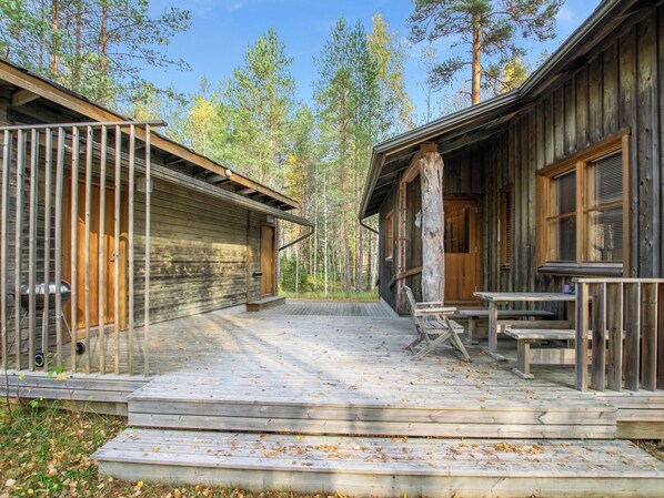 A wooden cabin with a porch, a table, and a chair.