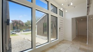 A spacious room with large windows, a modern chandelier, and a view of the outside.