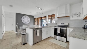 A modern kitchen with white cabinetry, a stainless steel stove, and a large island.