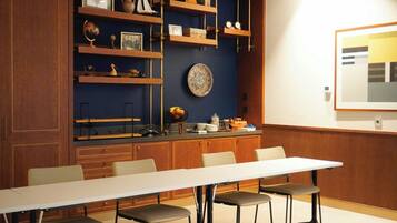 A conference room with a long table and four chairs, wooden shelves with various items, and a clock on the wall.