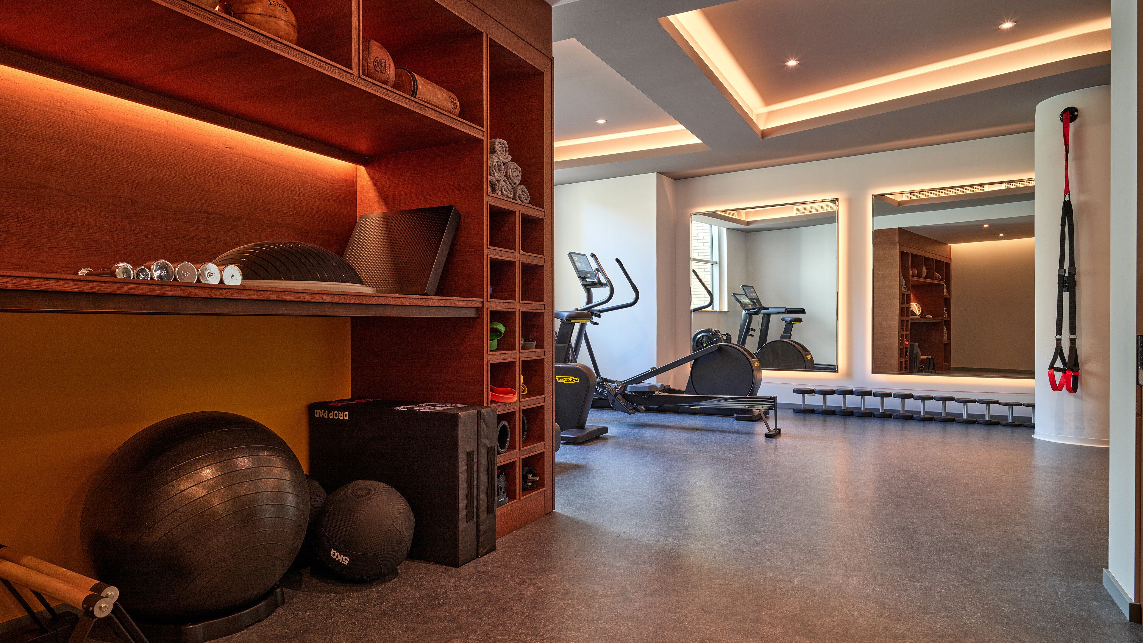 Ein Fitnessraum mit Trainingsgeräten, Laufband und Gewichten.