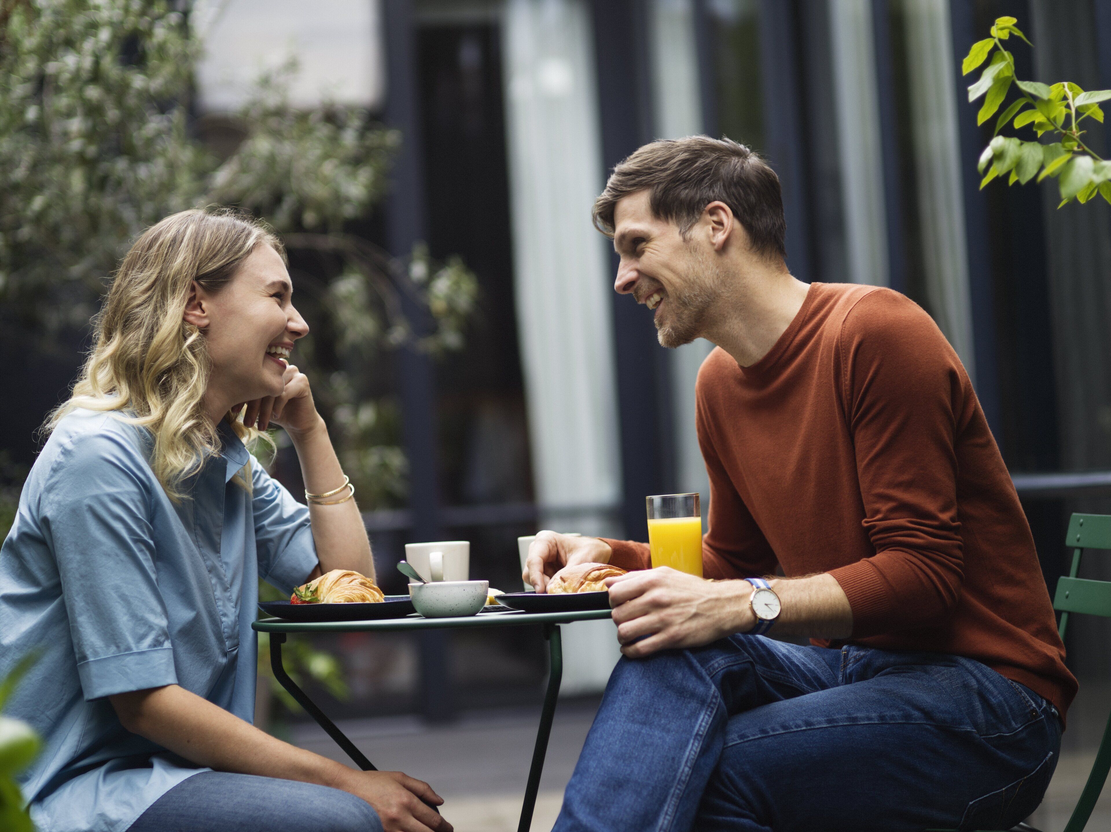 Zwei Personen sitzen an einem Tisch im Freien und essen und trinken.