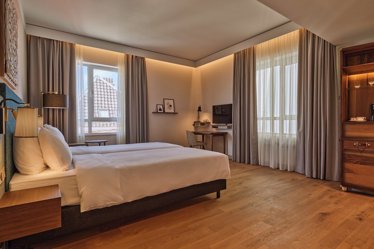 A hotel room with a bed, desk, and wardrobe.