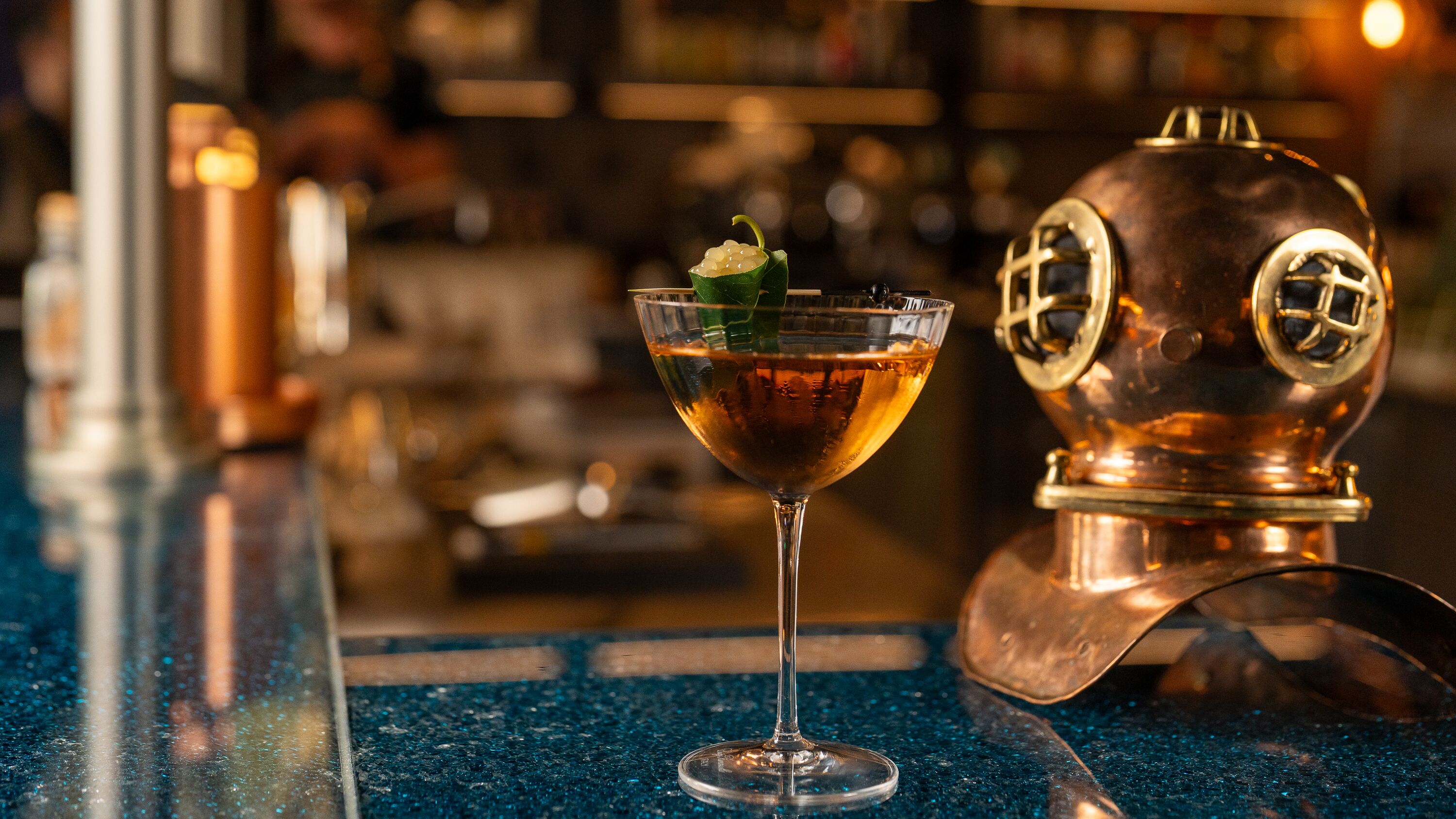 A bar setting with a cocktail glass and a copper distillation still.