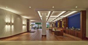 A spacious lobby with wooden flooring, a reception desk, and a blue accent wall. - voco The Hague by IHG (The Hague)