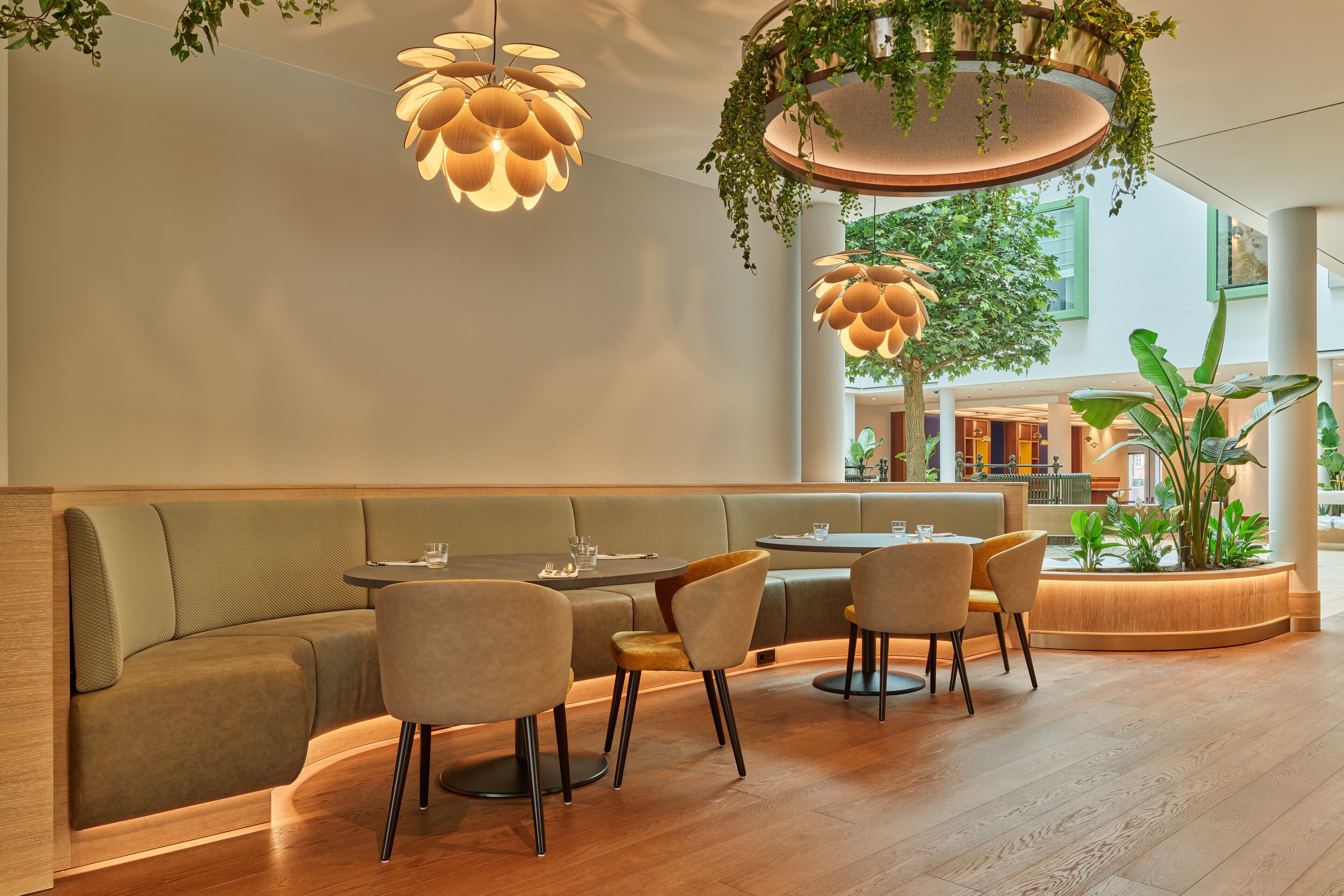 Un intérieur moderne avec un coin salon, un plancher en bois et des plantes suspendues.