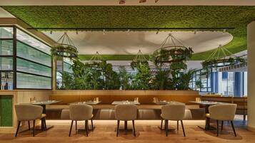 A restaurant with a green ceiling, hanging plants, and a modern seating arrangement.