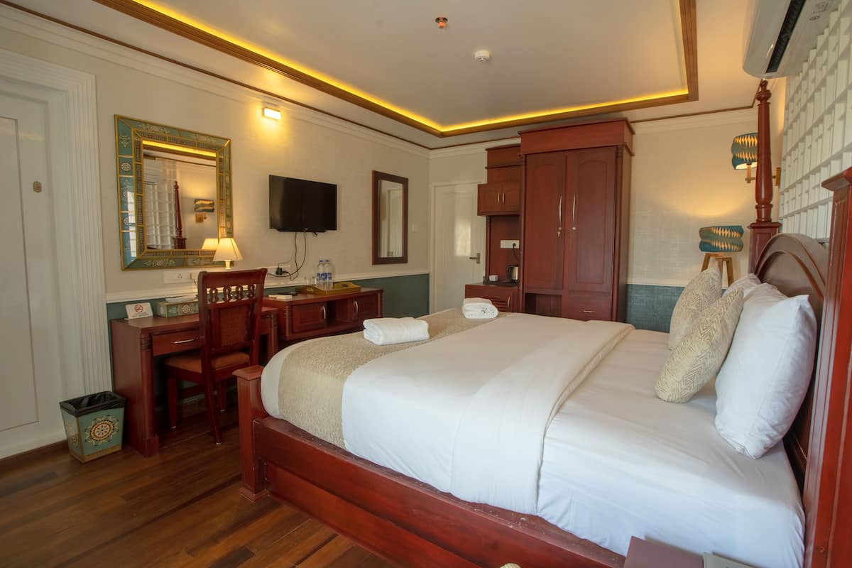 Una habitación de hotel con una cama grande, un escritorio de madera y televisión.