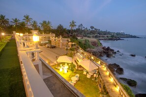 A beachfront resort with outdoor seating, a pool, and a view of the ocean. - State Beach Resort & Spa (Kannur)
