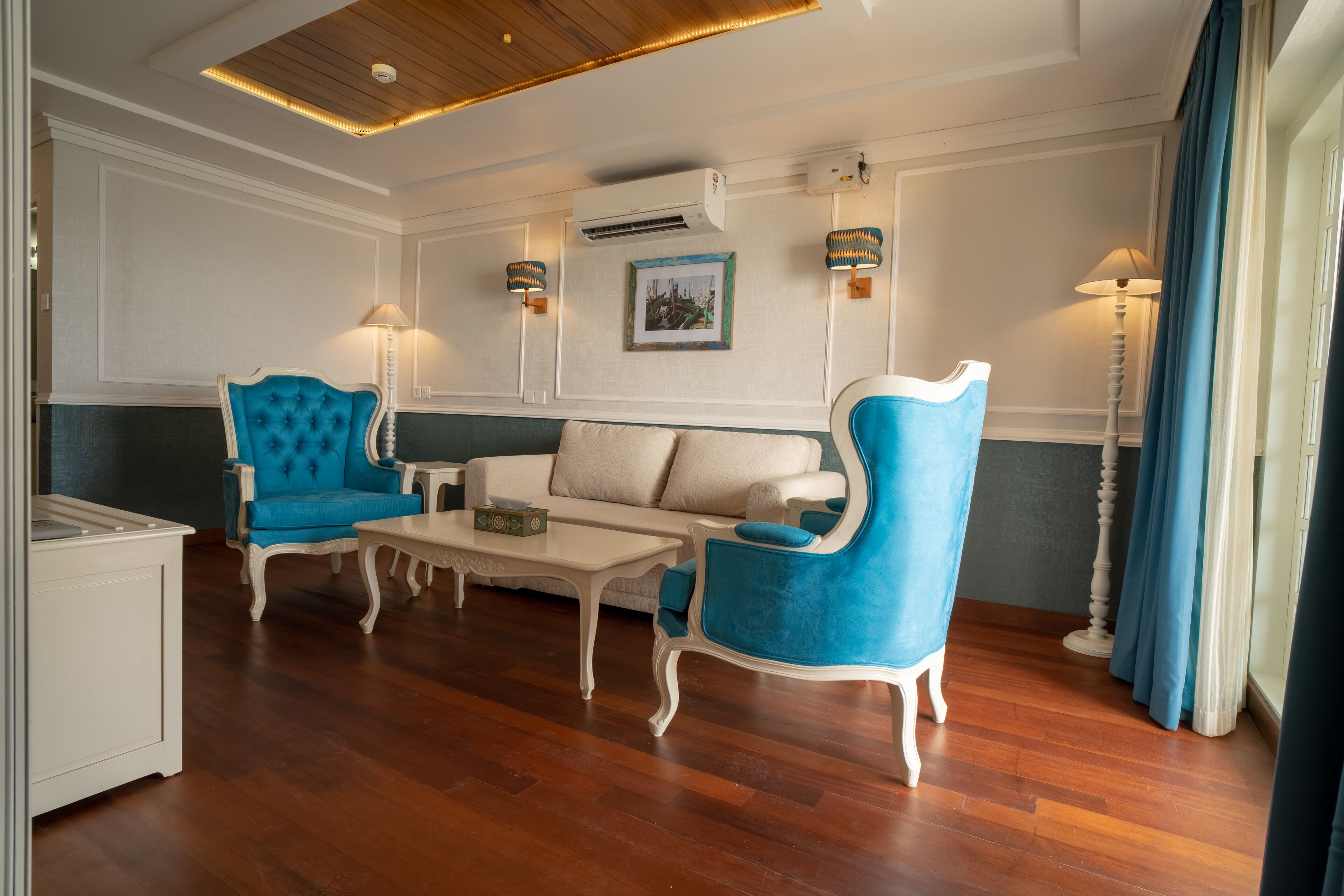 Un salon bien éclairé, comprenant un canapé, deux fauteuils, une table basse et une table d’appoint.