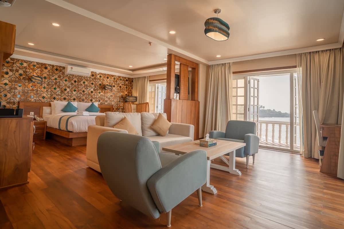 Amplia sala de estar con piso de madera, un conjunto de sofás, una mesa de centro y vista al mar a través de amplios ventanales.
