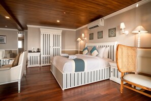 A bedroom with a bed, a chair, a desk, and an air conditioning unit.