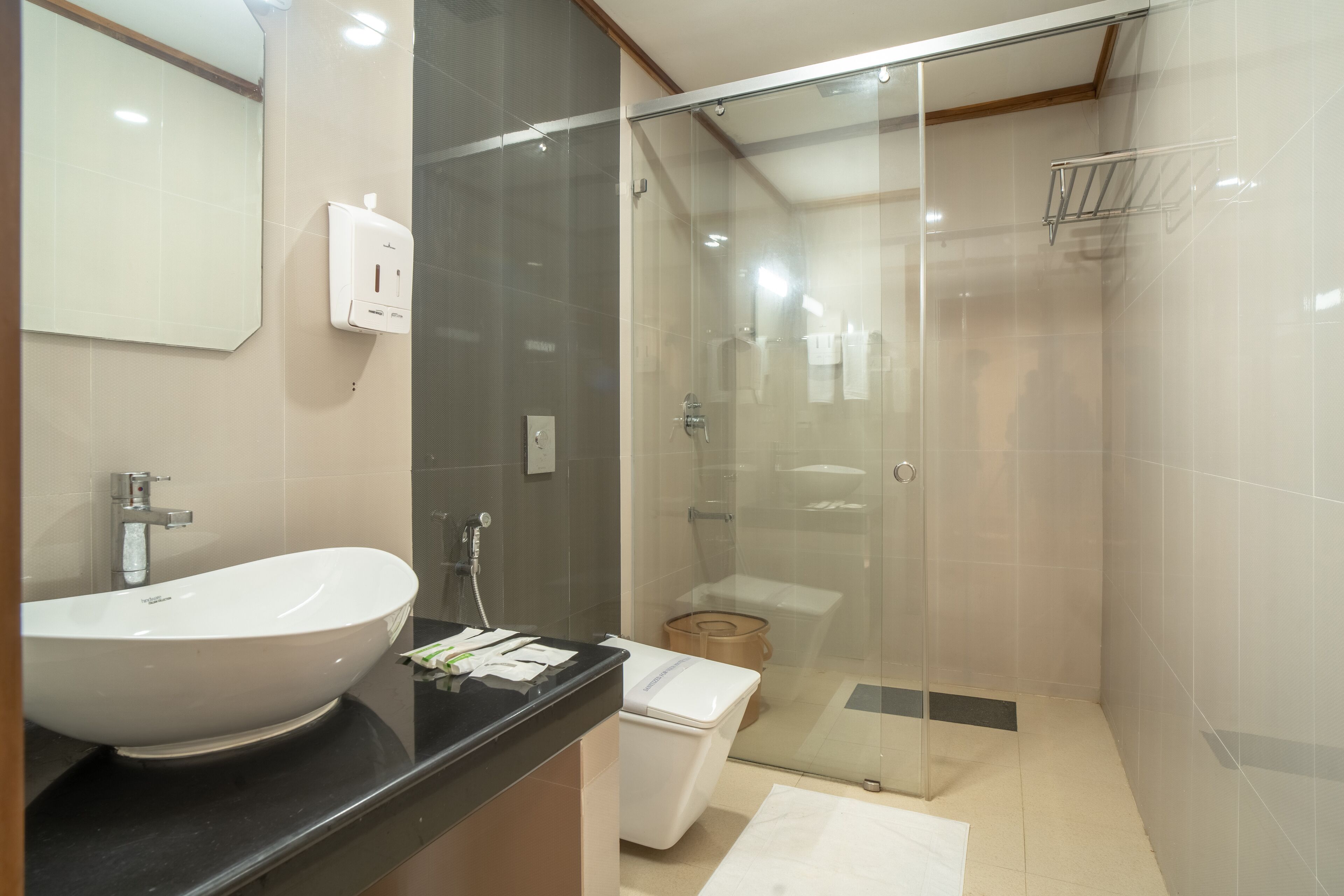 Een moderne badkamer met een groot wit wastafel, een douche met glazen wand en een toilet.