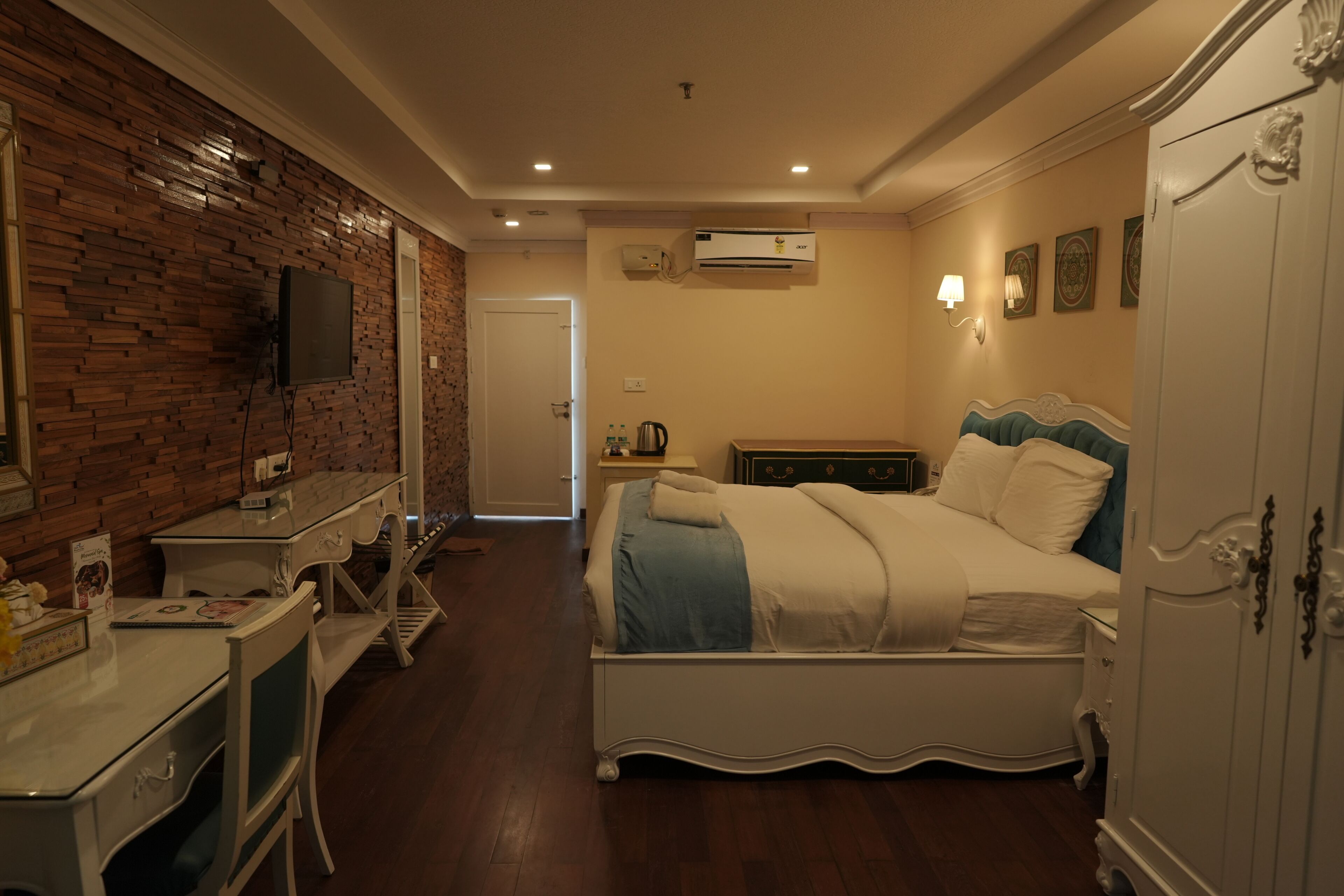 Una camera da letto con un letto, una scrivania, una sedia, un armadio e una televisione appesa al muro.