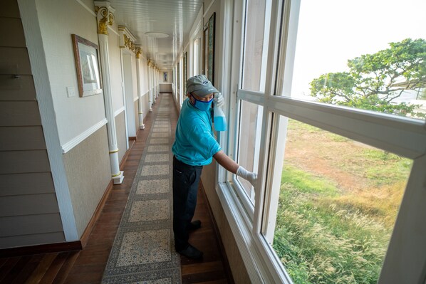 A corridor with a wooden floor and white walls, leading to a window with a view of a grassy area. - State Beach Resort & Spa (Kannur)