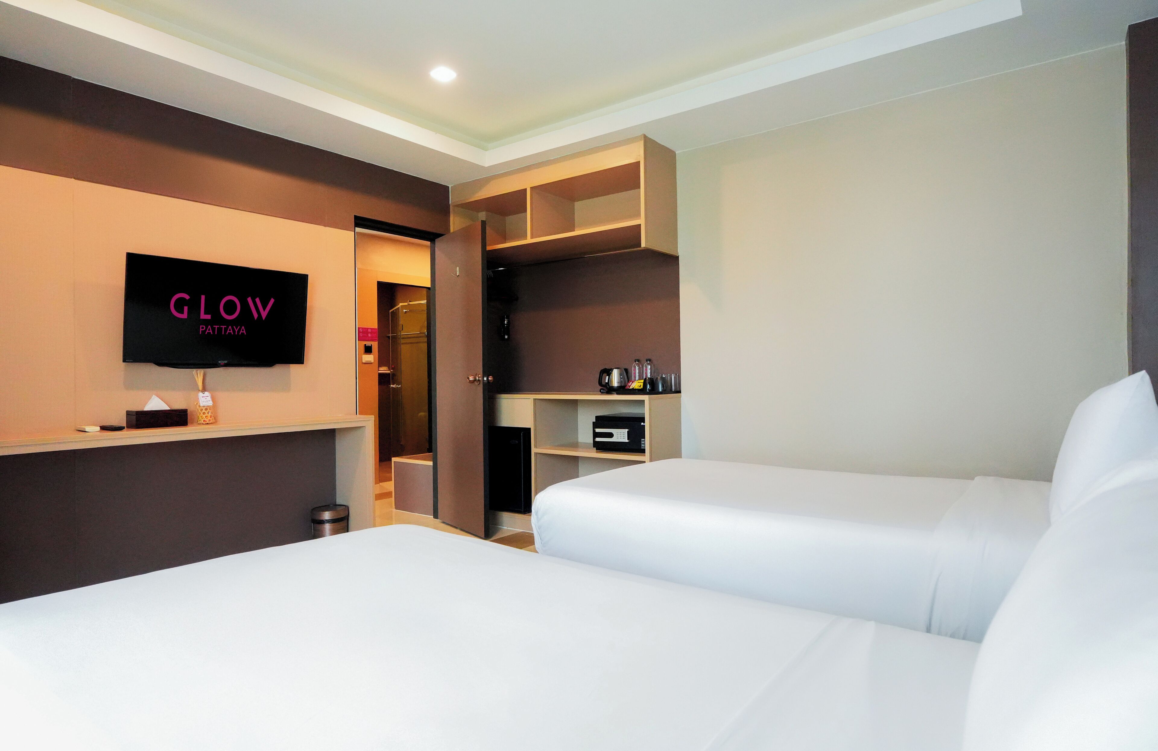 A hotel room with two beds, a TV, a minibar, and a wardrobe.