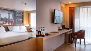 A hotel room with a bed, desk, chair, TV, and a painting of a cityscape. - GLOW Pattaya (Pattaya)