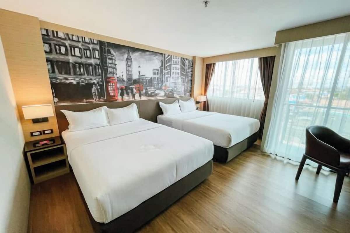 A hotel room with two beds, a painting of a cityscape, a chair, and a nightstand.