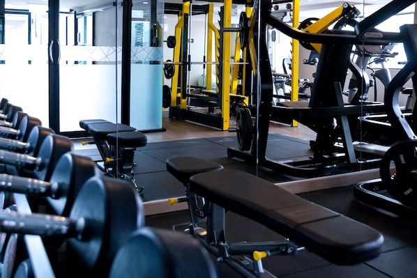 Un gimnasio con diversos equipos de ejercicio, incluyendo mancuernas, bancos y máquinas de pesas.