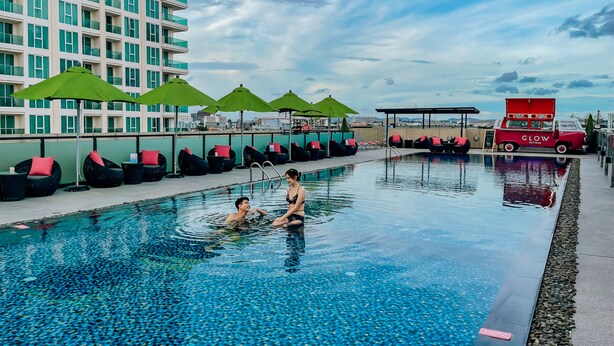 A swimming pool with tiled flooring, lounge chairs, and umbrellas. - GLOW Pattaya (Pattaya)