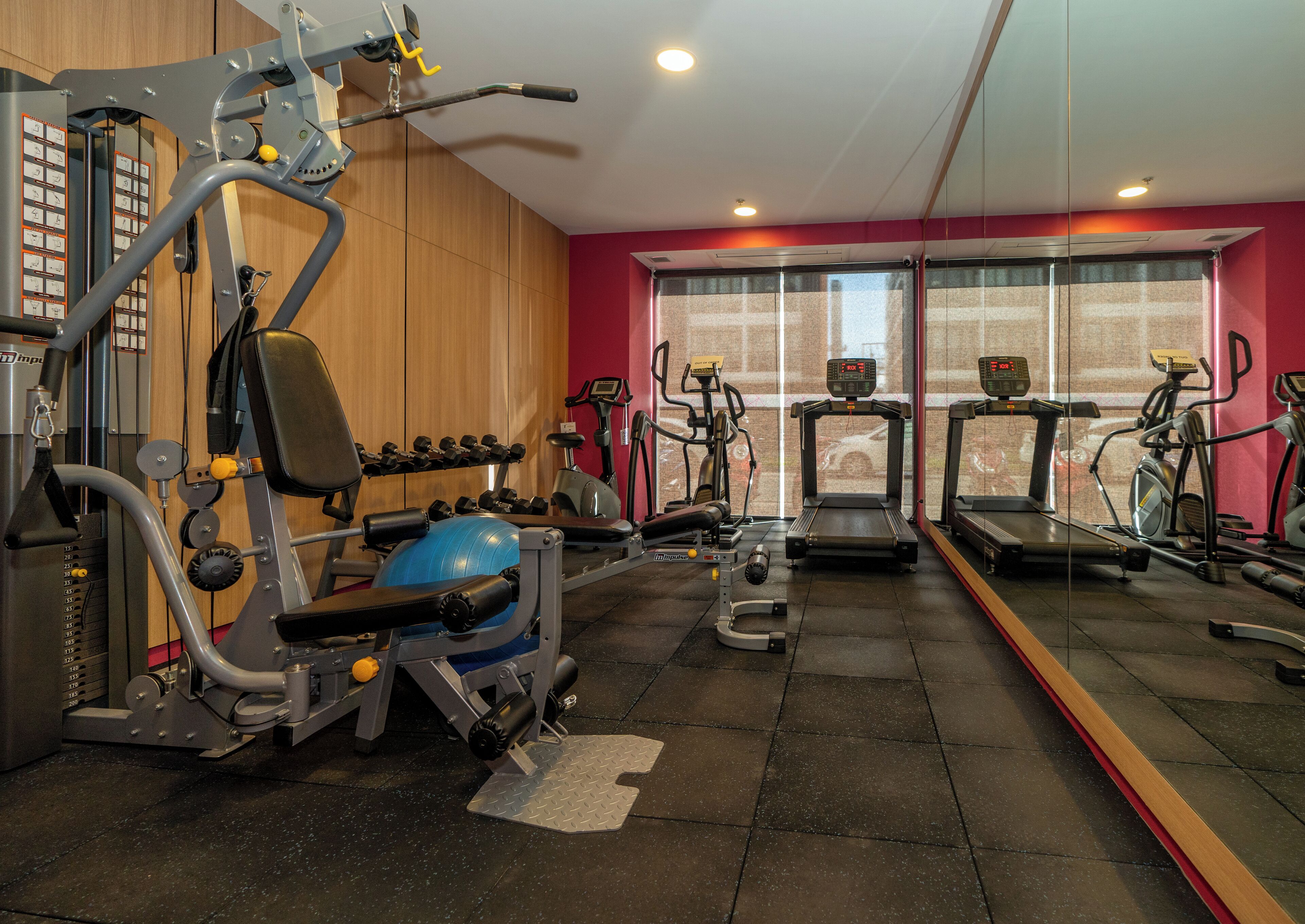 Una palestra con diverse attrezzature per l'allenamento, tra cui tapis roulant, manubri e macchinari per pesi.