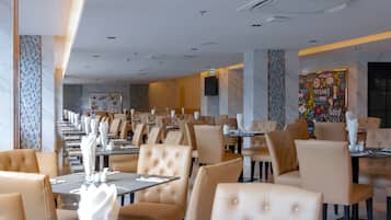 Un restaurante moderno con un amplio comedor, mesas tipo cabina y mesas altas.