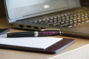 Ein Laptop, ein Stift und ein Notizbuch auf einem Holztisch.