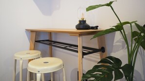 A small workspace with a wooden desk, two stools, a lamp, and a plant. - Luana Shibuya (Tokyo)