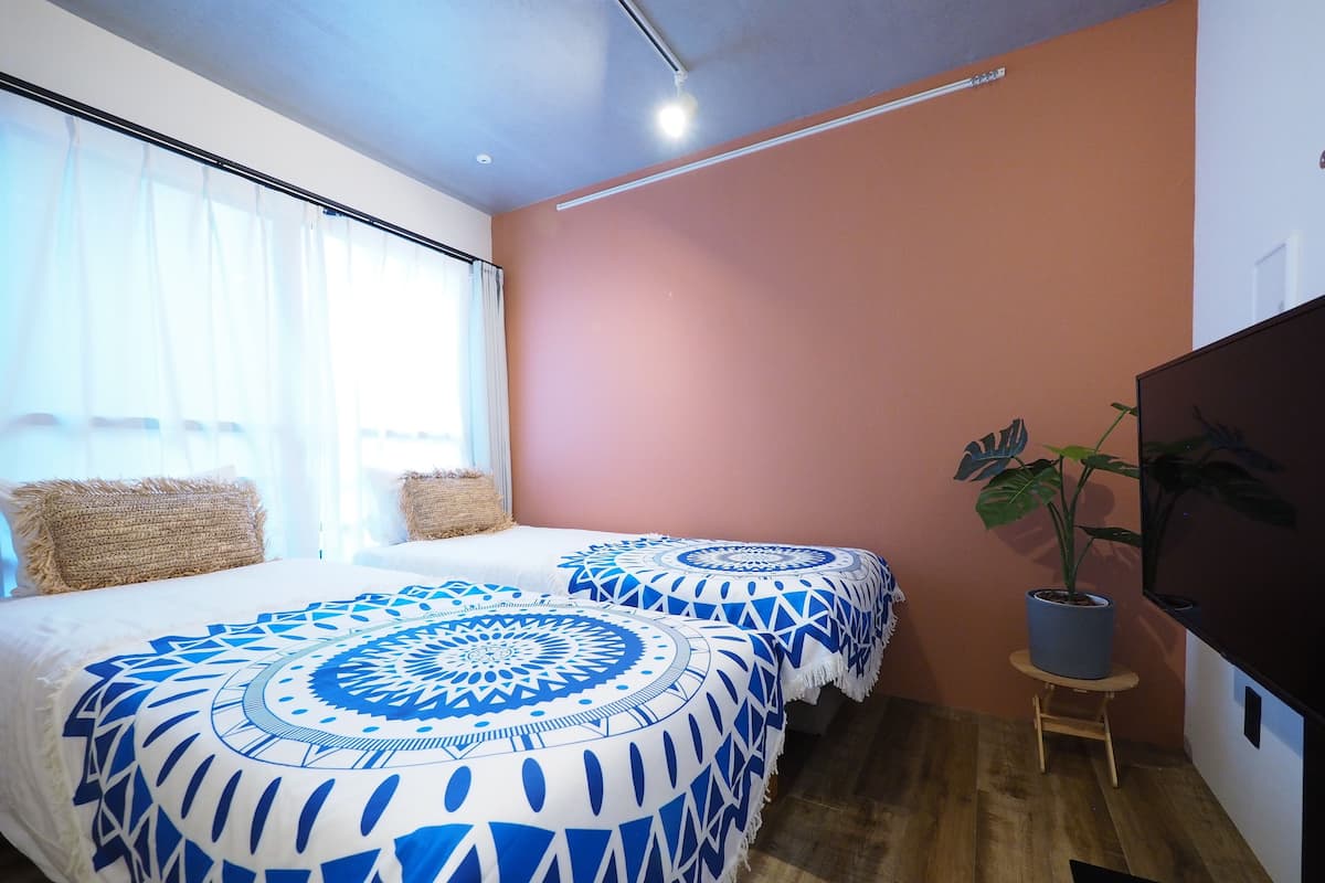 Quarto com duas camas, televisão e um vaso de planta.