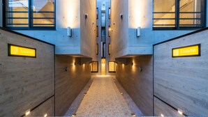 A hallway with wooden walls and a tiled floor, leading to a central elevator area. - Luana Shibuya (Tokyo)