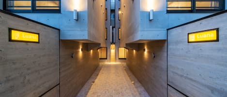 A hallway with wooden walls and a tiled floor, leading to a central elevator area.