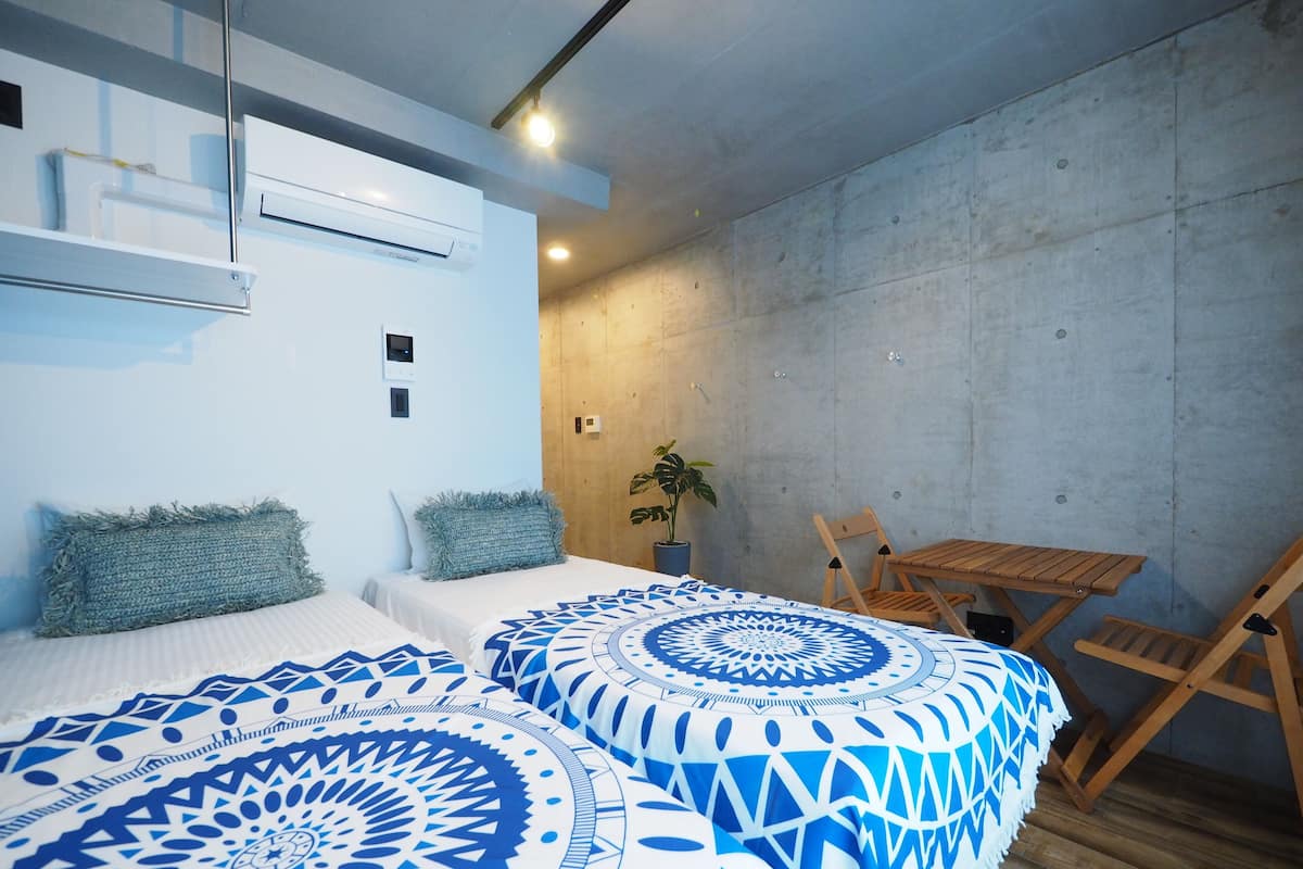 Quarto moderno com duas camas, uma mesa de madeira e uma cadeira.