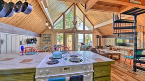 A kitchen with a stove, a dining area with chairs, and a view of the outdoors.