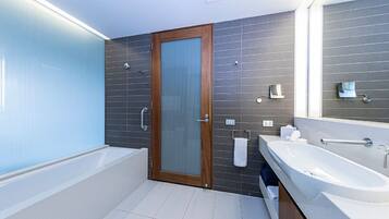 A modern bathroom with a bathtub, a large mirror, and a vanity with a sink.